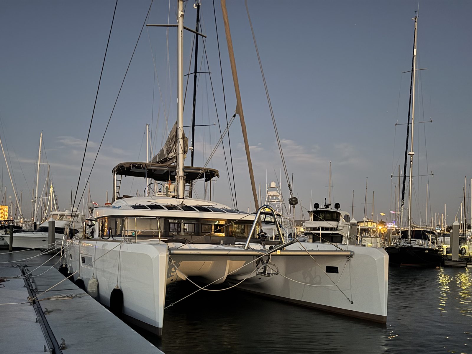 Subdivisions, a Lagoon 52F sail catamaran, docked bow-on in her marina slip at dusk