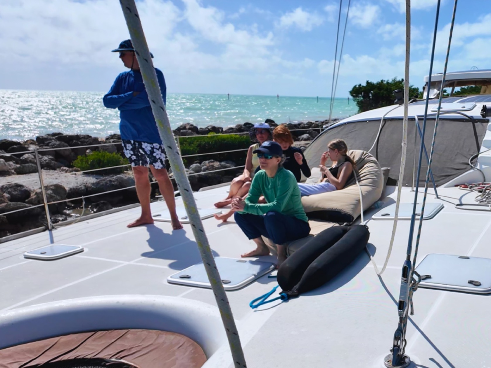 A cruiser talking with guests on the bow of a catamaran